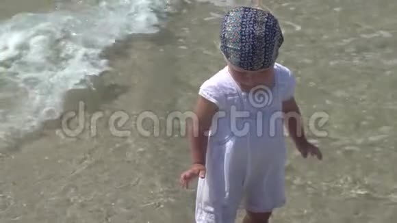 一个孩子站在海水里穿着白色连衣裙的小女孩在海水中散步视频的预览图