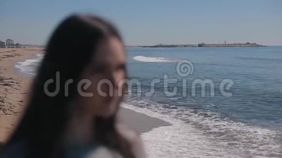 海滩上一个年轻女孩的形象她戴上太阳镜图像变得集中海洋开始视频的预览图