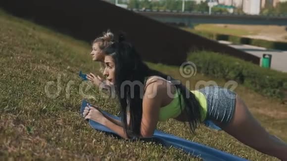健身妇女在晨公园慢动作瑜伽垫上做木板运动视频的预览图