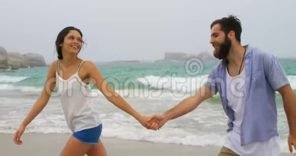 高加索夫妇手牵手在海滩散步的正面景色视频的预览图