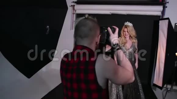 摄影师拍摄一个女孩模特金发穿着漂亮的裙子在工作室视频的预览图