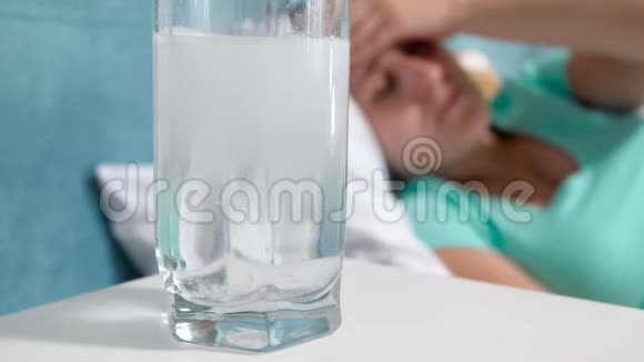 在床头柜上用溶解阿司匹林药物的4k杯水的特写镜头视频的预览图