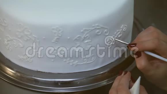 糖果师在白色结婚蛋糕上画奶油花视频的预览图