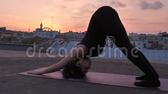 夏天日落时分瑜伽女孩站在屋顶向下的狗健康的生活方式放松的观念冥想视频的预览图