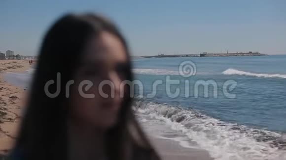 在晴朗的晴天一个女孩在海滩和大海的风景下模糊的肖像女孩戴上太阳镜重点视频的预览图