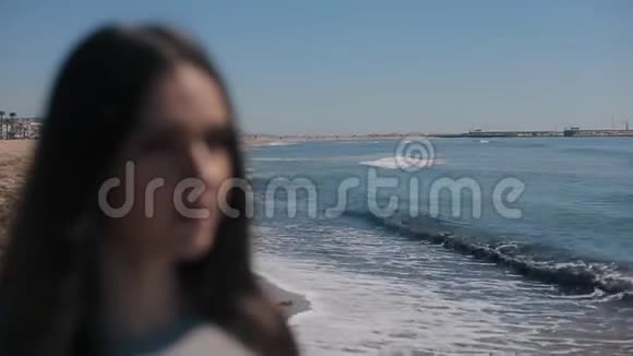 一个头发长长的女孩模糊的特写镜头欣赏着海浪飞溅的海景女人穿上了视频的预览图