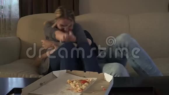 漂亮的年轻夫妇坐在靠近披萨的沙发上视频的预览图