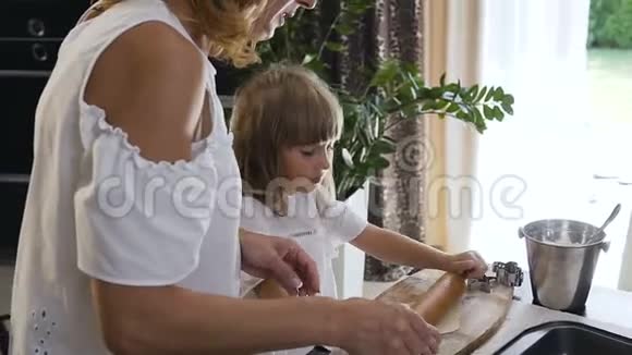 一位美丽的母亲教她的小女儿做饭在桌子上捏一个面团做饼干视频的预览图