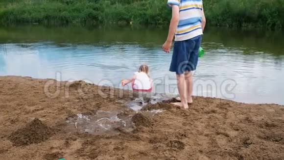 小朋友夏天在河里玩耍小女孩从河里捡起水把水倒进沙子里视频的预览图