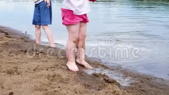 小女孩和男孩用水桶从河里打水动作缓慢孩子们在沙滩上玩大自然视频的预览图