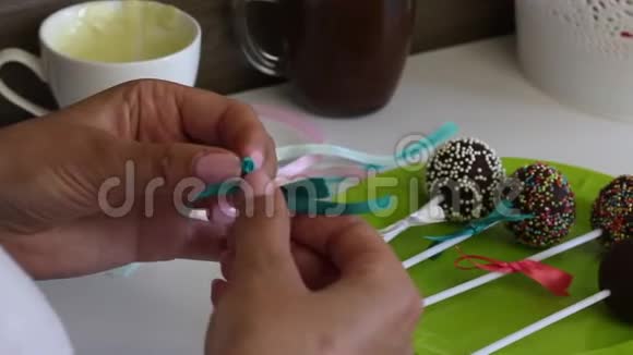 一个女人在盘子里装饰辫子蛋糕的蝴蝶结不同颜色的糖果装饰视频的预览图