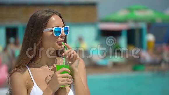 夏天美丽的年轻女子比基尼女孩在热带游泳池放松快乐的女人喝异国情调的鸡尾酒视频的预览图