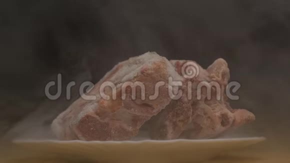 黑色背景上的一块块冷冻旋转的肉从这块肉中吹出霜冻的新鲜和寒冷烟雾特写缓慢视频的预览图