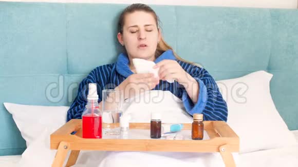 4K镜头显示年轻女性感到恶心躺在床上使用大量药物使用咽喉和鼻腔喷雾剂的妇女视频的预览图