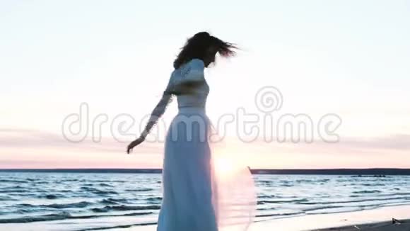 美丽的欧洲新娘带着一束手工制作的原始花束在日落时在海上旋转新婚快乐的女人视频的预览图