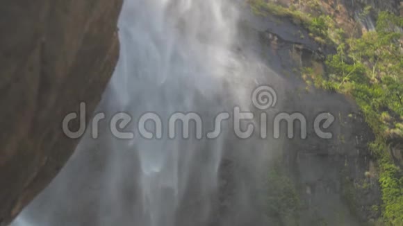 从棕色的岩石后面可以看到湿石瀑布视频的预览图