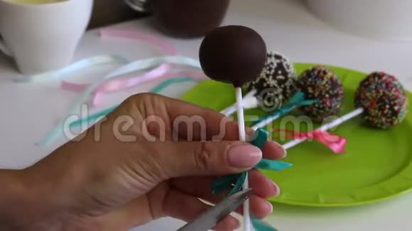 一个女人用辫子蛋糕的蝴蝶结装饰然后把它放在盘子里用不同颜色的糖果装饰视频的预览图