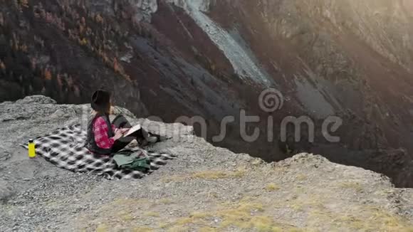 女徒步旅行者在山顶悬崖上使用数码平板电脑视频的预览图