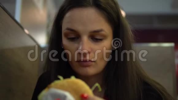 饥饿的女孩吃汉堡包快餐店的女人咬芝士汉堡视频的预览图