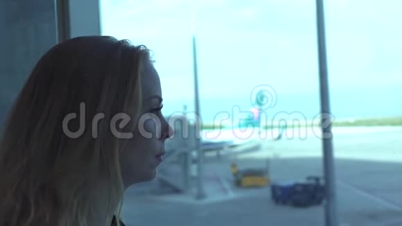 女旅客在候机室的飞机上寻找机场候机窗口年轻女孩一边看着窗户视频的预览图