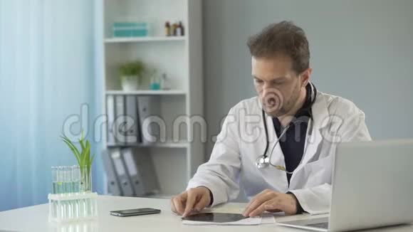 整形外科医生坐在桌子旁看鼻骨x光医疗保健视频的预览图