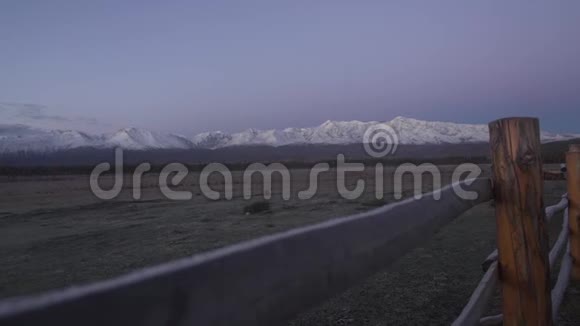 美丽的风景清晨的群山中霜落在前景的木栅栏上雪沉郁的山峰上视频的预览图