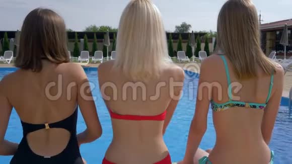 在游泳池附近的露台上穿着泳衣享受夏天的日光浴女孩视频的预览图