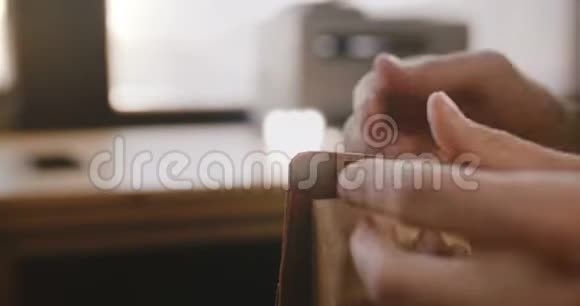 近景男手缝制手工皮包在马鞍与针在轻现代制造车间视频的预览图