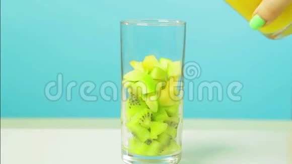 在一个杯子里切几维果片和一个苹果然后倒入橙汁玻璃旋转成圆视频的预览图