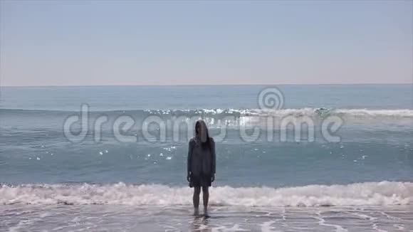 一位美丽的模特赤脚走出大海岸边波涛汹涌慢动作视频的预览图