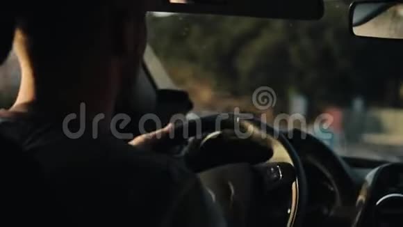 一位留着胡须的年轻男性司机转动方向盘的后景外面模糊的图像视频的预览图