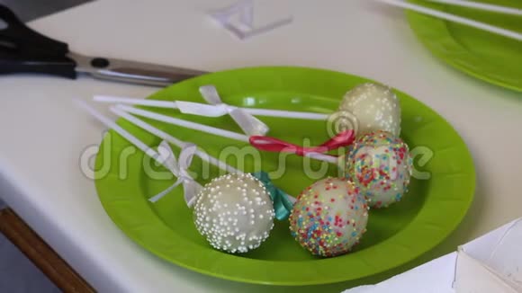 一个女人在盘子里装饰辫子蛋糕的蝴蝶结用不同颜色的糖果装饰视频的预览图