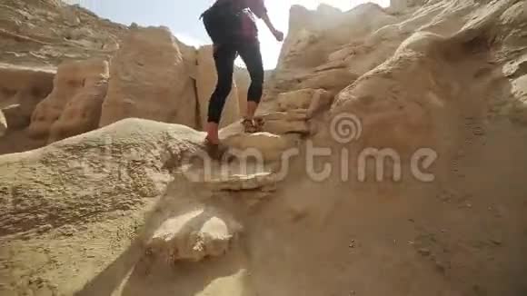 女人的腿在大沙漠石头上行走女人爬上沙漠岩石山后景视频的预览图