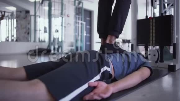 在健身房里男人的腿踩在躺着的男人的背上视频的预览图