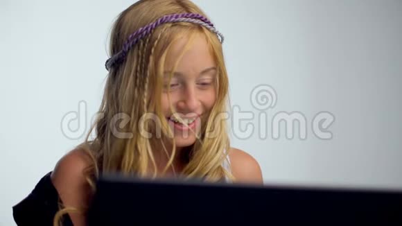 快乐的年轻女子坐在地板上用灰色背景的笔记本电脑视频的预览图