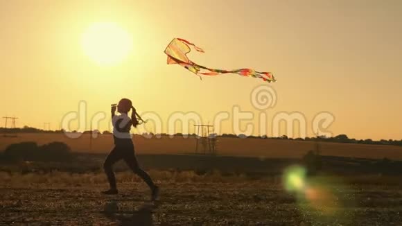 美丽的年轻女孩带着风筝在夕阳下奔跑视频的预览图