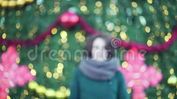 美丽的年轻女孩带着大围巾在冬天在户外微笑圣诞节的灯光背景户外冬季肖像画视频的预览图