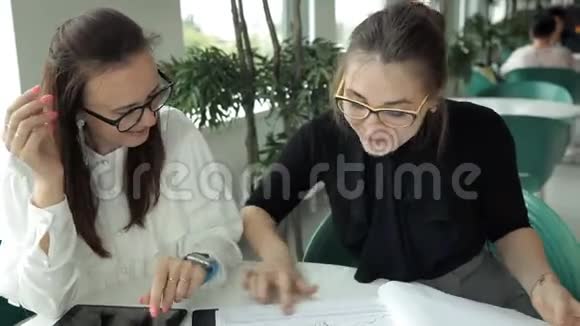 两个年轻的商业女孩坐在咖啡馆里讨论生意请服务员接近他们工作午餐视频的预览图