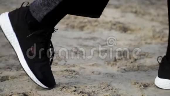 在沙滩上行走的时尚运动鞋中收拢双腿慢动作稳定射击概念鞋视频的预览图