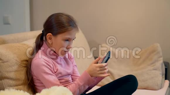 一个10岁的女孩正在智能手机上玩手机游戏视频的预览图
