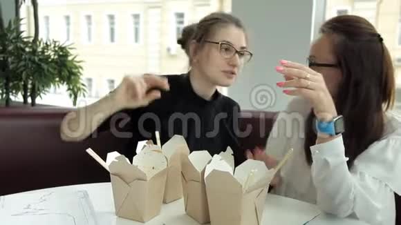 两个戴着眼镜的女商人坐在咖啡馆里吃着中国菜一个侍者走过来向他要账单视频的预览图