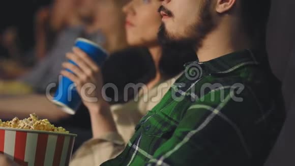 有胡子的年轻人在电影院吃爆米花视频的预览图