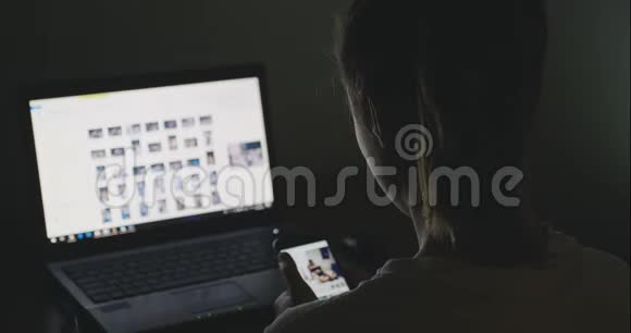 一位年轻的商务女性深夜在家中使用笔记本电脑和智能手机视频的预览图