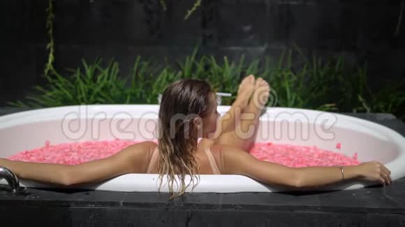 照片拍摄于金发女孩在室外温泉浴场享受夏日时光的背后视频的预览图