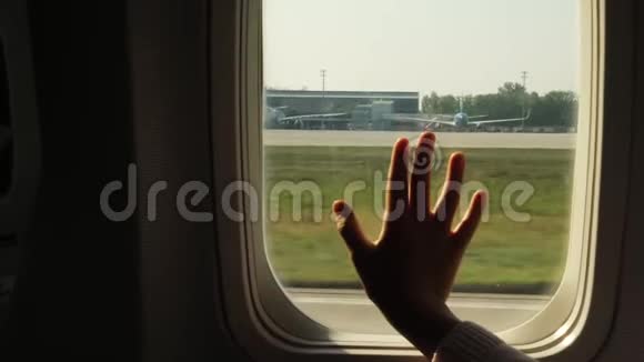 孩子的手碰到飞机窗户关上一个孩子手掌的剪影在窗户的背景下视频的预览图