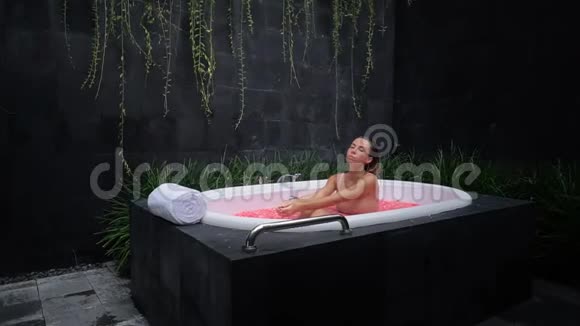 在浴缸中摆姿势的模特花浴黑石浴的水疗程序视频的预览图