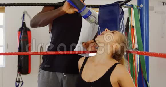 男子驯兽师给拳击场的女拳击手喂水视频的预览图