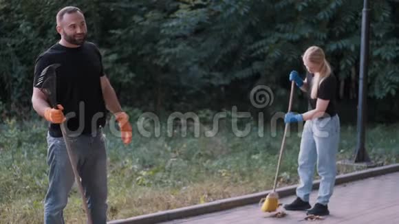 志愿者在当地公园用扫帚清扫泥土和干叶视频的预览图