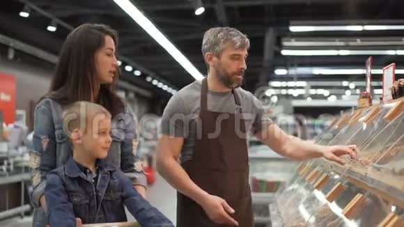 妈妈和孩子在超市里买烤卷售货员穿着围裙把食物放进塑料袋里视频的预览图