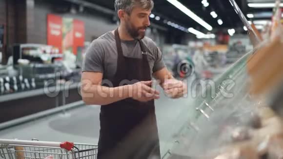 超级市场的帅哥正在从购物车里拿甜甜圈然后把它们放在货架上视频的预览图
